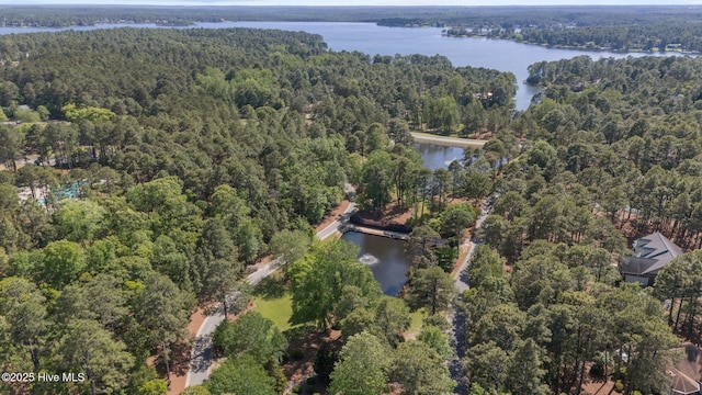 aerial view of property and surrounding area with a heavily wooded area and a nearby body of water