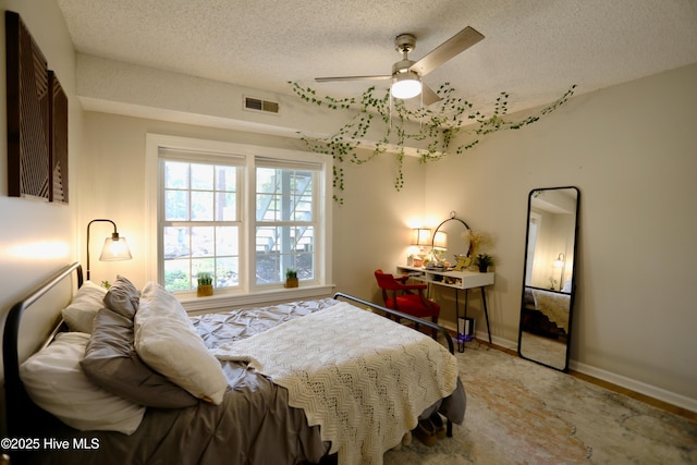 bedroom featuring a textured ceiling, baseboards, ceiling fan, and light wood-style flooring