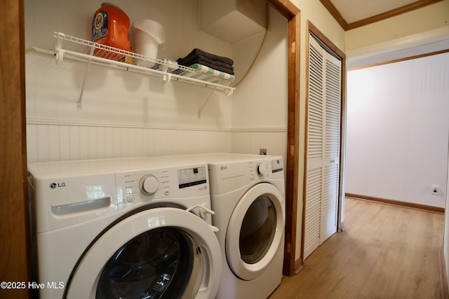 laundry area featuring separate washer and dryer, light wood-type flooring, wainscoting, and ornamental molding