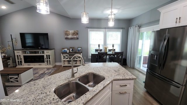 kitchen featuring black fridge, a sink, open floor plan, wood finished floors, and white cabinets