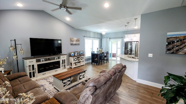 living area with a ceiling fan, wood finished floors, baseboards, recessed lighting, and vaulted ceiling