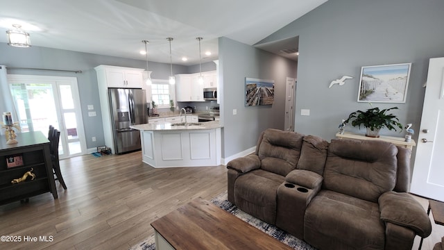living room featuring light wood finished floors, baseboards, lofted ceiling, and recessed lighting