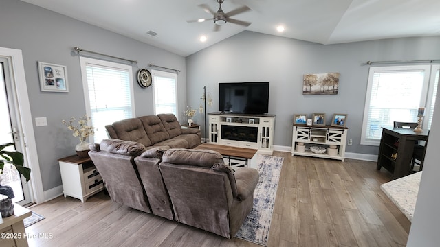 living area with ceiling fan, wood finished floors, vaulted ceiling, and baseboards