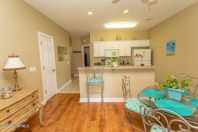 139 Avian Dr Unit 3614, Sunset Beach, NC 28468 - kitchen with white appliances, a breakfast bar, white cabinetry, light countertops, and recessed lighting