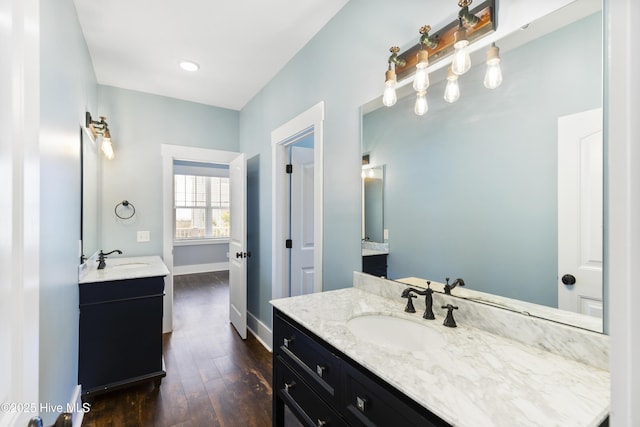 full bathroom with two vanities, wood finished floors, and baseboards