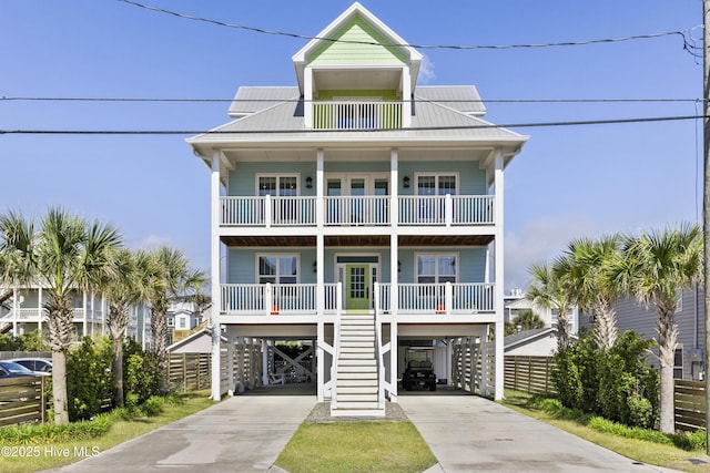 coastal home featuring a carport, a balcony, a porch, and driveway