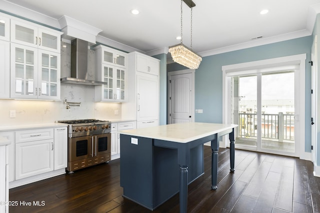 kitchen featuring double oven range, wall chimney range hood, dark wood finished floors, light countertops, and ornamental molding