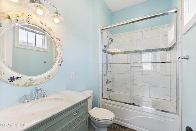 full bath featuring toilet, vanity, and combined bath / shower with glass door