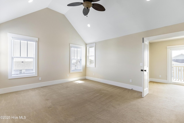 empty room with a ceiling fan, lofted ceiling, light colored carpet, healthy amount of natural light, and baseboards