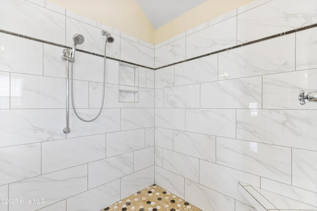 bathroom with a tile shower and vaulted ceiling