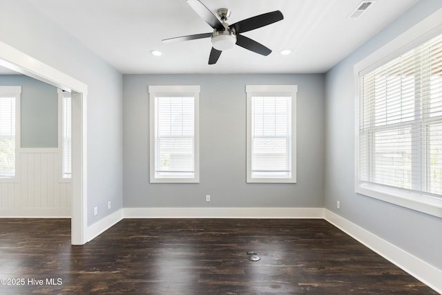 empty room with plenty of natural light, ceiling fan, dark wood-type flooring, wainscoting, and recessed lighting