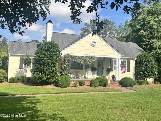 310 N Franklin St, Whiteville, NC 28472 - view of front of house featuring a front lawn, covered porch, a shingled roof, and a chimney
