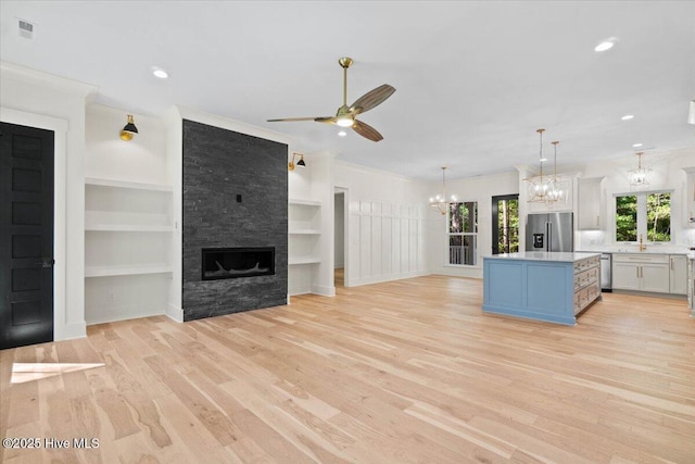 kitchen featuring stainless steel appliances, a chandelier, light countertops, a center island, and a ceiling fan
