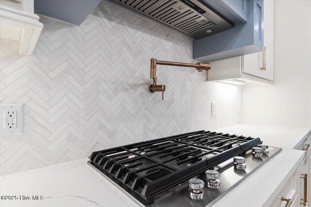kitchen view of stainless steel gas cooktop, white cabinets, and light stone countertops
