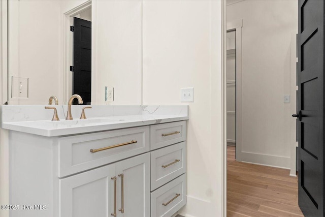 bathroom with wood finished floors, baseboards, and vanity