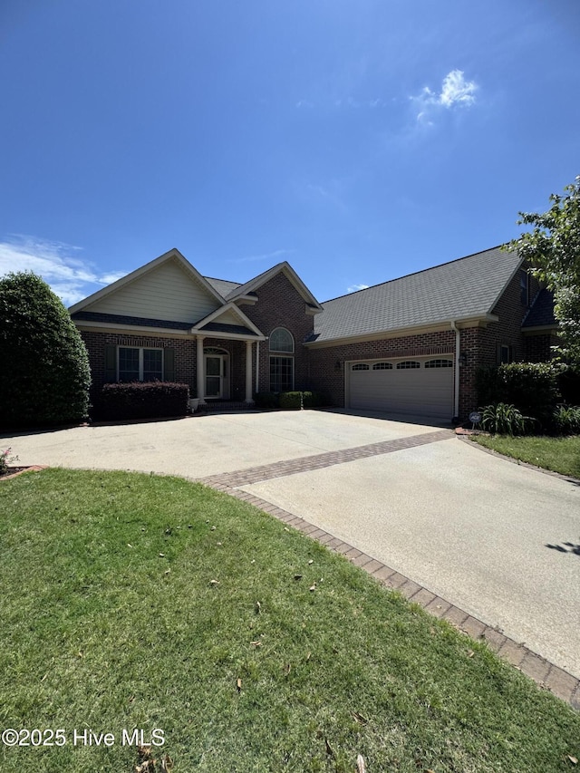 view of front of house featuring brick siding, a garage, driveway, and a front lawn