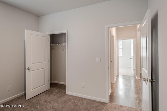unfurnished bedroom with attic access, baseboards, carpet, and a closet
