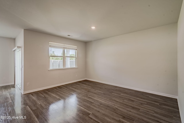 spare room featuring dark wood-style flooring, baseboards, and recessed lighting