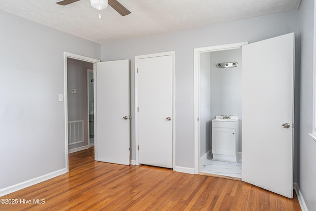 137 Pinecrest Trl, Rockingham, NC 28379 - unfurnished bedroom featuring wood finished floors, baseboards, ensuite bath, a sink, and a textured ceiling