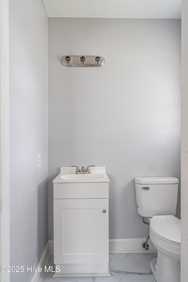 137 Pinecrest Trl, Rockingham, NC 28379 - half bath featuring toilet, vanity, marble look tiles, and baseboards