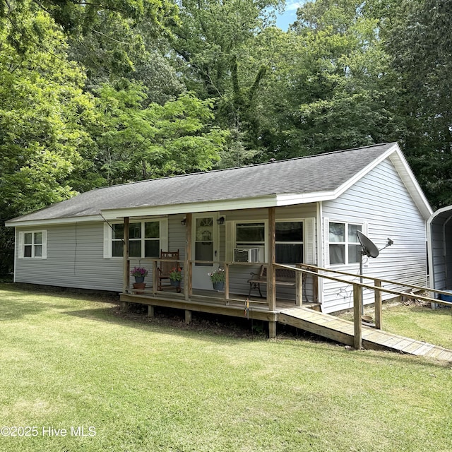 rear view of property with a yard, roof with shingles, and a carport