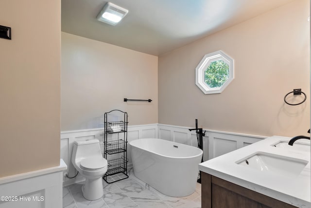 338 Country Club Rd, Camden, NC 27921 - bathroom featuring marble look tiles, a freestanding bath, wainscoting, toilet, and a decorative wall
