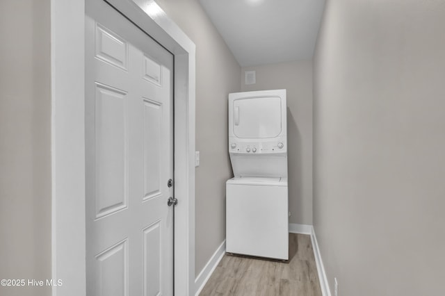 laundry area featuring estacked washer and dryer, baseboards, and light wood-style floors