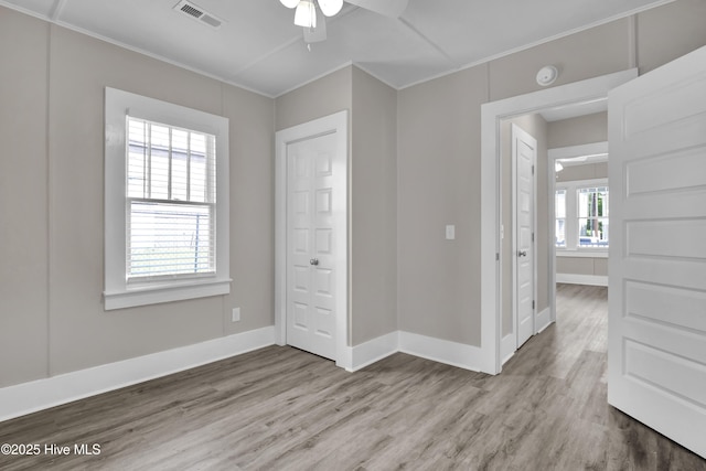 empty room with wood finished floors, ornamental molding, a ceiling fan, baseboards, and a smoke detector