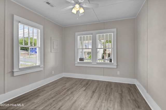 empty room with wood finished floors, crown molding, ceiling fan, and baseboards