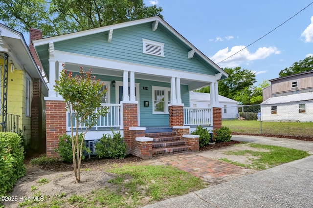 view of front of property with covered porch, fence, and brick siding