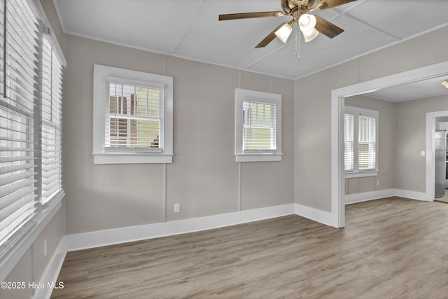 empty room with wood finished floors, baseboards, a ceiling fan, and ornamental molding