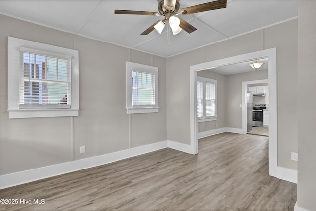 unfurnished room with crown molding, light wood-style floors, baseboards, and ceiling fan
