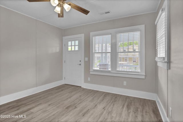 foyer entrance with wood finished floors, a ceiling fan, ornamental molding, and baseboards