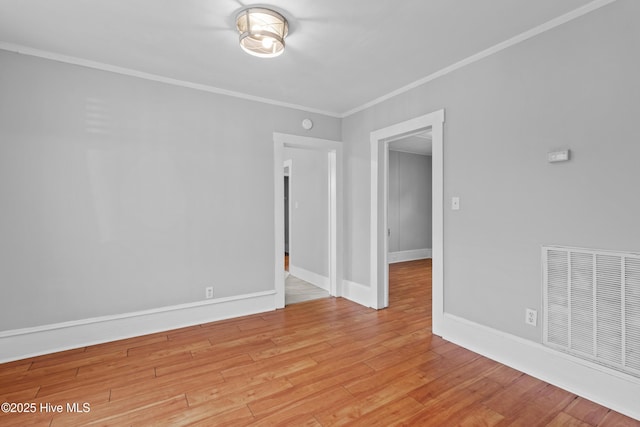 spare room with ornamental molding, light wood-style flooring, and baseboards