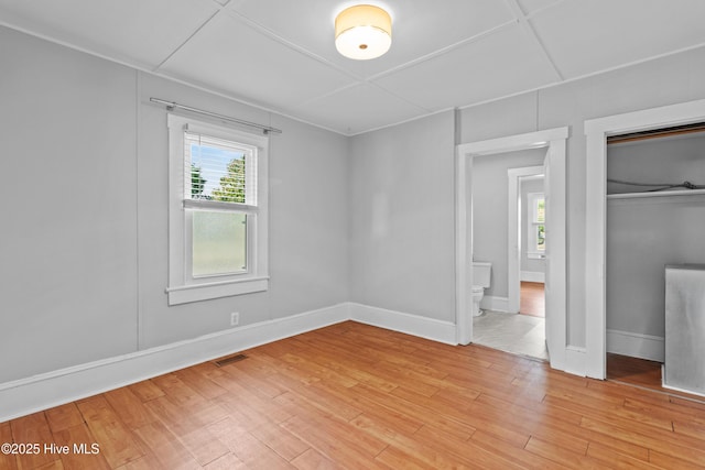 unfurnished bedroom featuring multiple windows, light wood-style flooring, and a closet