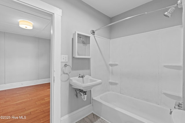 full bathroom with baseboards, shower / bath combination, wood finished floors, and a sink