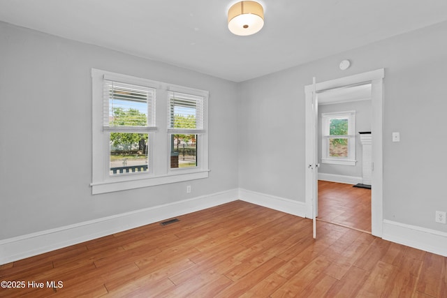 unfurnished room featuring light wood-style flooring, baseboards, and a smoke detector