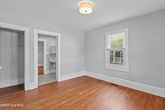unfurnished bedroom with light wood finished floors, baseboards, and a closet