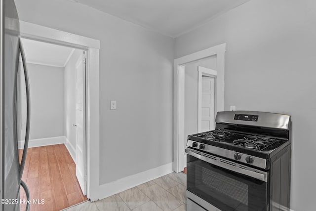 kitchen featuring gas stove, refrigerator, baseboards, and ornamental molding