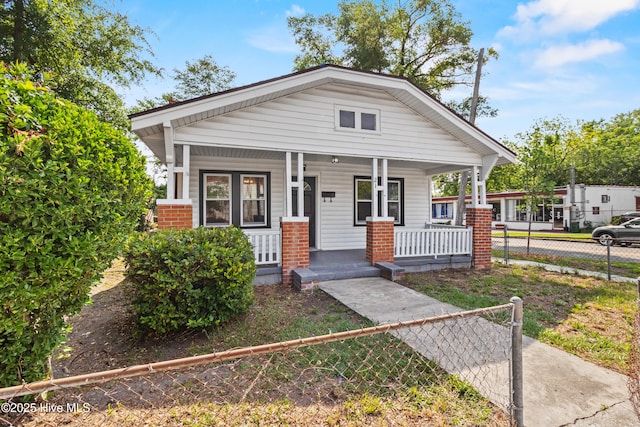 view of front of home featuring covered porch, a fenced front yard, and brick siding