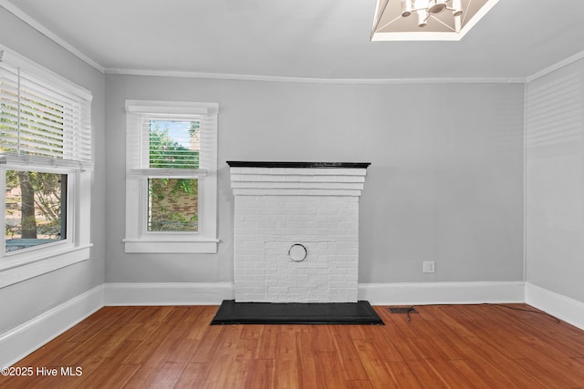 unfurnished room featuring wood finished floors, baseboards, ornamental molding, and a fireplace