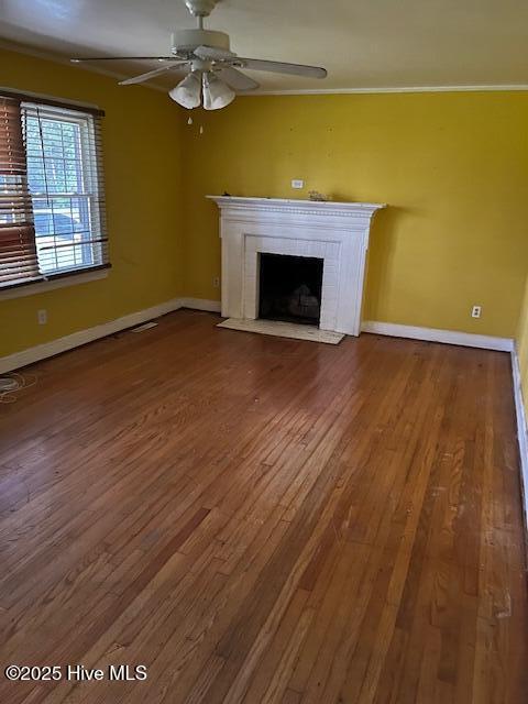 1616 Hwy 58 S, Snow Hill, NC 28580 - unfurnished living room featuring ceiling fan, wood finished floors, a tiled fireplace, and baseboards