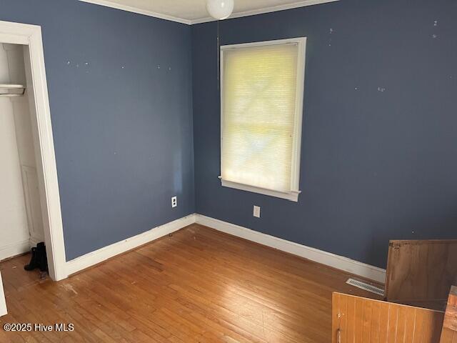 1616 Hwy 58 S, Snow Hill, NC 28580 - unfurnished bedroom featuring crown molding, wood finished floors, multiple windows, baseboards, and a closet