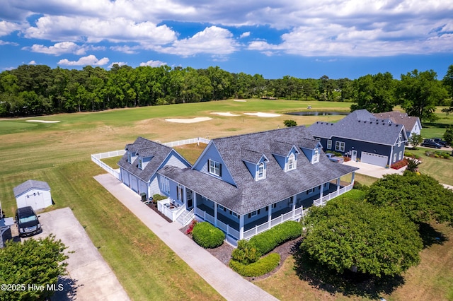 aerial view of a golf course, a tree filled landscape, and a nearby body of water