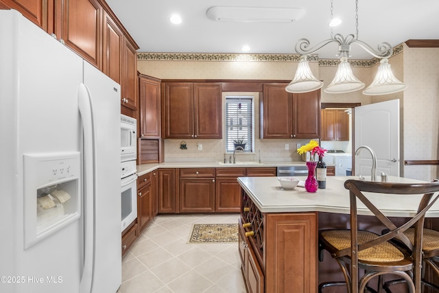 kitchen featuring white appliances, wallpapered walls, light countertops, a kitchen bar, and a sink