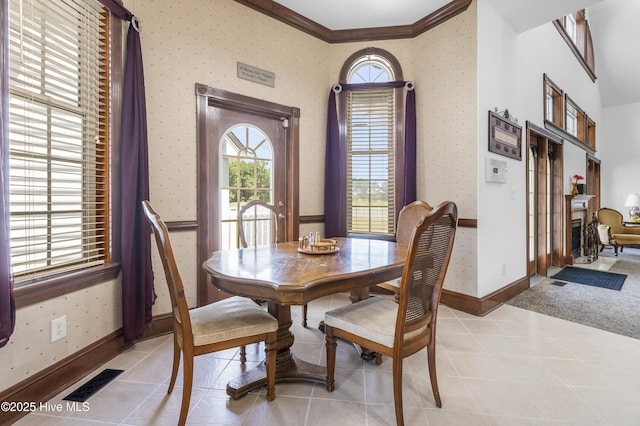 dining room with plenty of natural light, ornamental molding, wallpapered walls, baseboards, and light tile patterned floors