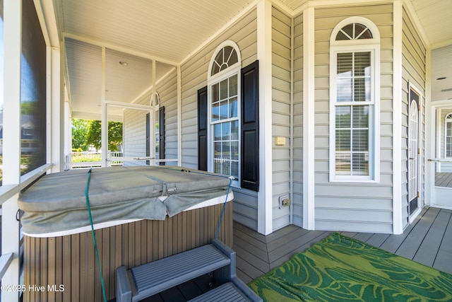 wooden deck featuring a hot tub and a porch