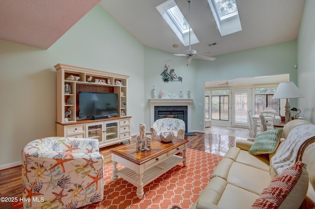 6025 Inland Greens Dr, Wilmington, NC 28405 - living room with high vaulted ceiling, a glass covered fireplace, wood finished floors, baseboards, and a skylight