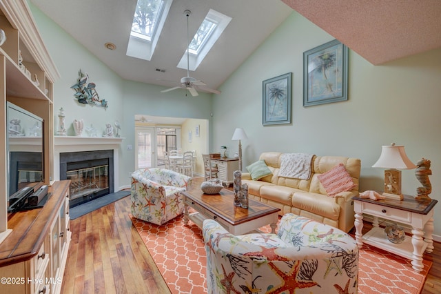 6025 Inland Greens Dr, Wilmington, NC 28405 - living area with a glass covered fireplace, light wood-type flooring, a skylight, a ceiling fan, and baseboards
