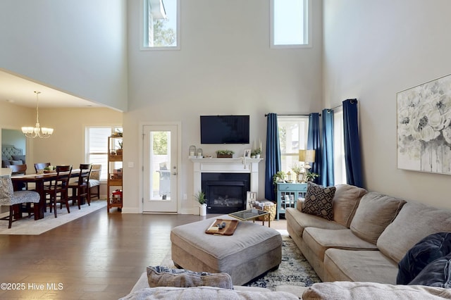 living room featuring a high ceiling, healthy amount of natural light, a glass covered fireplace, and dark wood-type flooring
